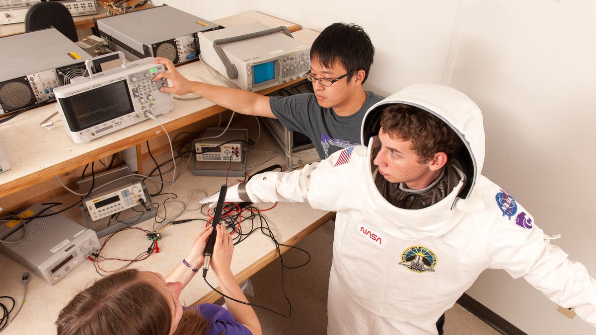Kansas State University engineering students work  with a model spacesuit