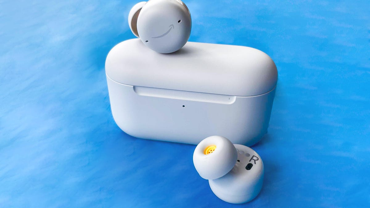 A pair of white Amazon Echo earbuds and charging case against a blue background. 