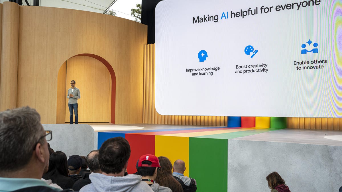 Sundar Pichai stands to the left of a giant screen that says "Making AI helpful for everyone"