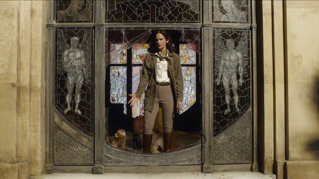 Ruth Wilson as Mrs Coulter, standing in a church window, reaching down toward her monkey