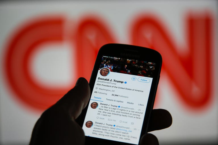 Donald Donald Trump's Twitter timeline is seen on a smartphone against a backdrop with the CNN log