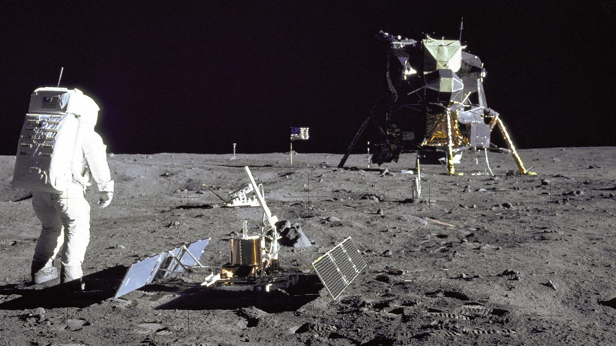 Apollo 11 astronaut Buzz Aldrin stands on the moon next to seismic measurement gear, steps away from the lunar module Eagle.