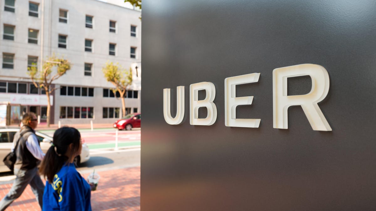 People walk down Market Street past sign with logo at the headquarters of ride-sharing technology company Uber in the South of Market (SoMa) neighborhood of San Francisco, California. Uber acknowledges it had a legal obligation to disclose a hack affecting 57 million users. The concealed hack puts them under a microscope with state and federal regulators.
