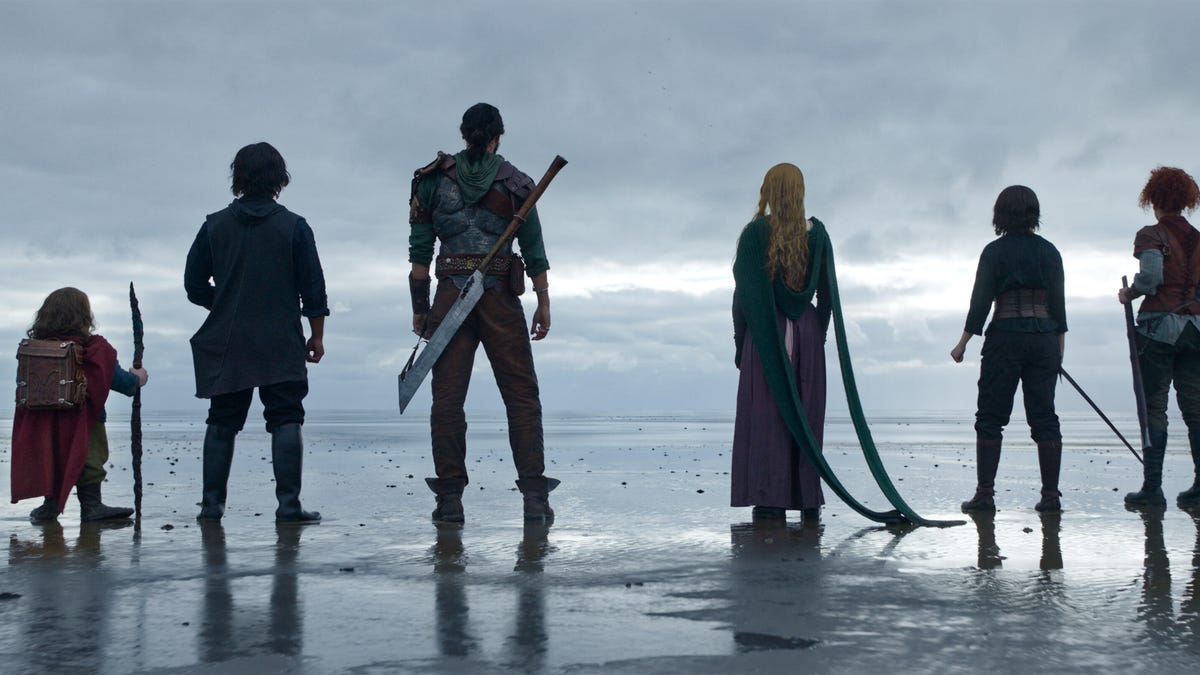 Characters in the Willow TV series stand on a wet, expansive beach looking into the distance