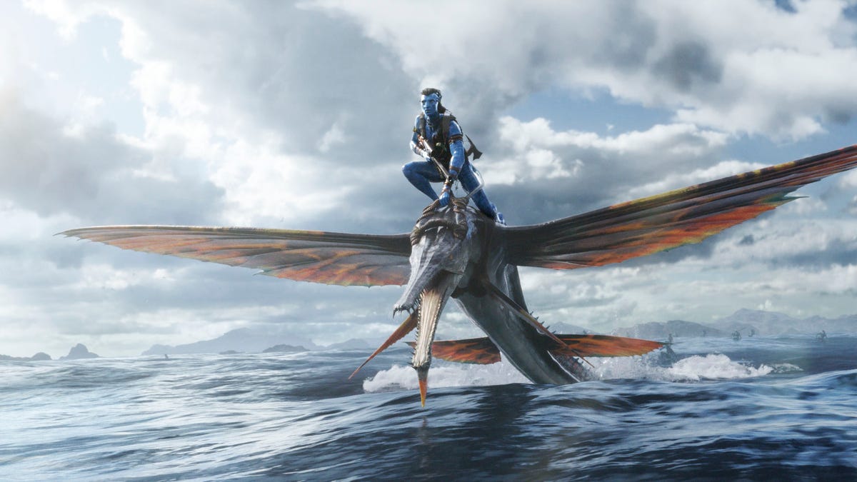 A blue alien rides a flying fish across the sea in Avatar 2 The Weight of Water.