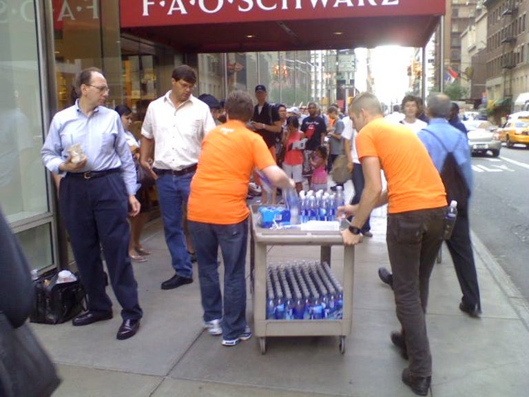 Apple store employees (in orange) hand out free SmartWater to people in line.