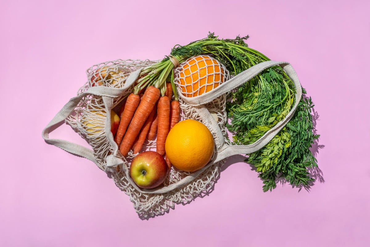 an arrangement of fruits and veggies on a pink background