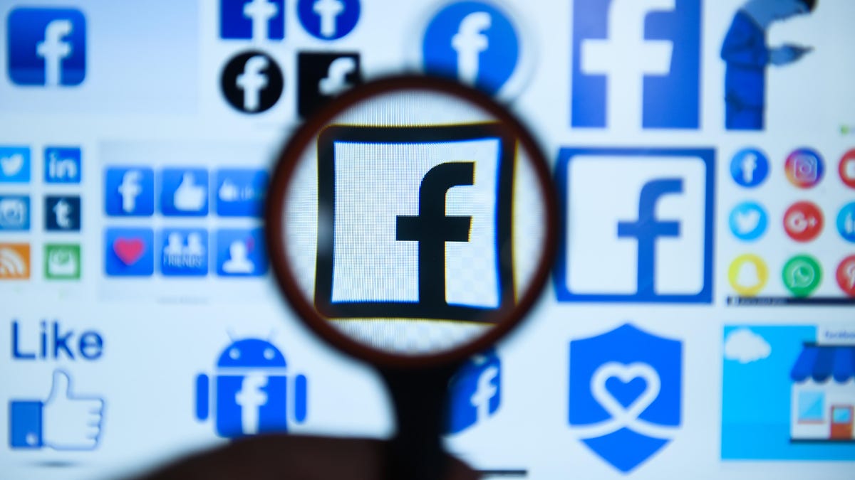 Facebook  logo is seen trough a magnifying glass on a