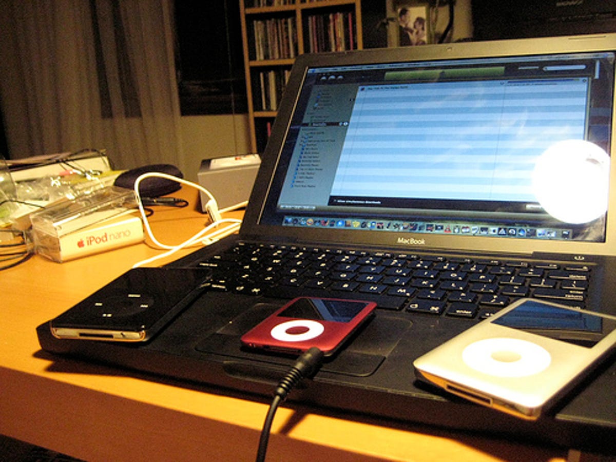 Photo of laptop, iTunes, and three iPods.