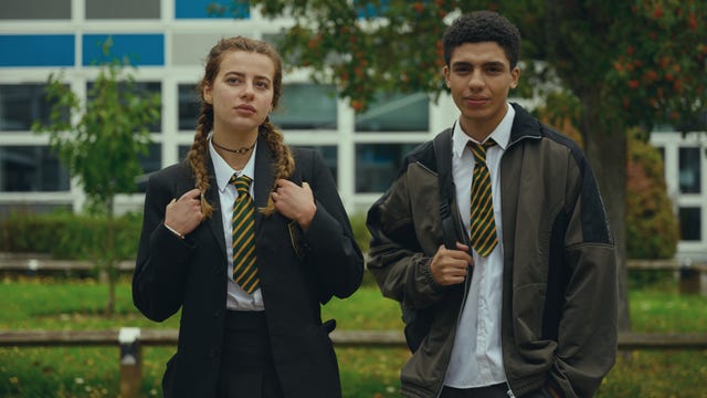 A female and male school student standing outside