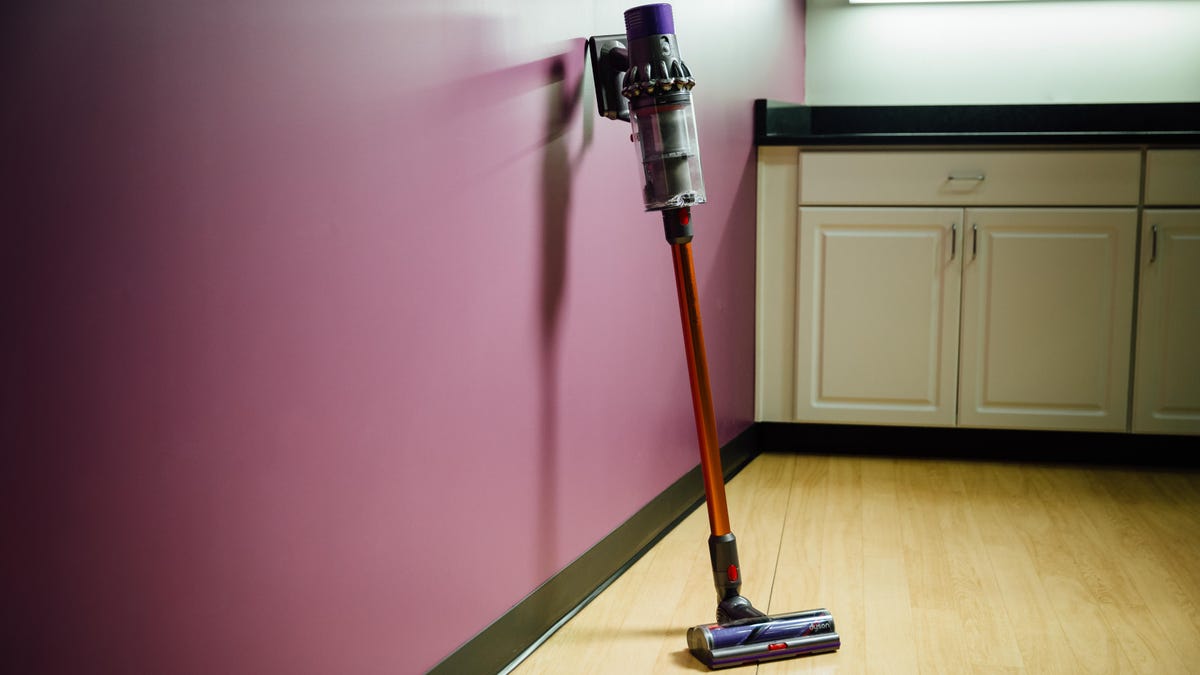 Dyson V10 cordless vacuum leaning against a wall.