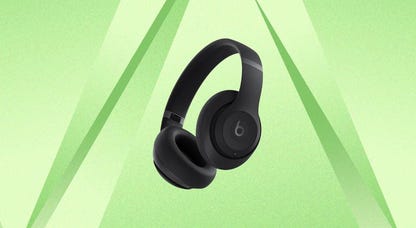 A pair of black Beats Studio Pro headphones against a green background.