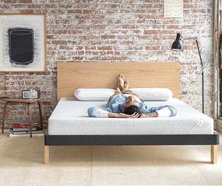 Man laying on Tuft and Needle Nod bed in front of exposed brick wall