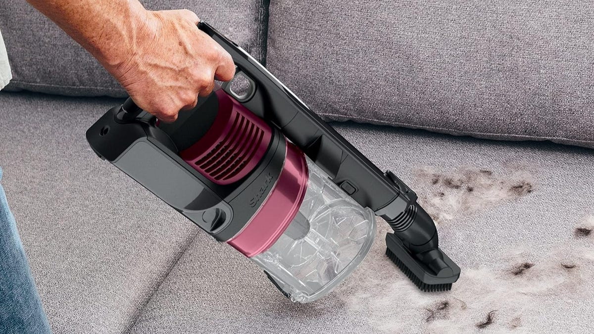 The Shark Rocket Pet Pro Cordless Vac with the brush attachment cleaning pet hair from a couch.