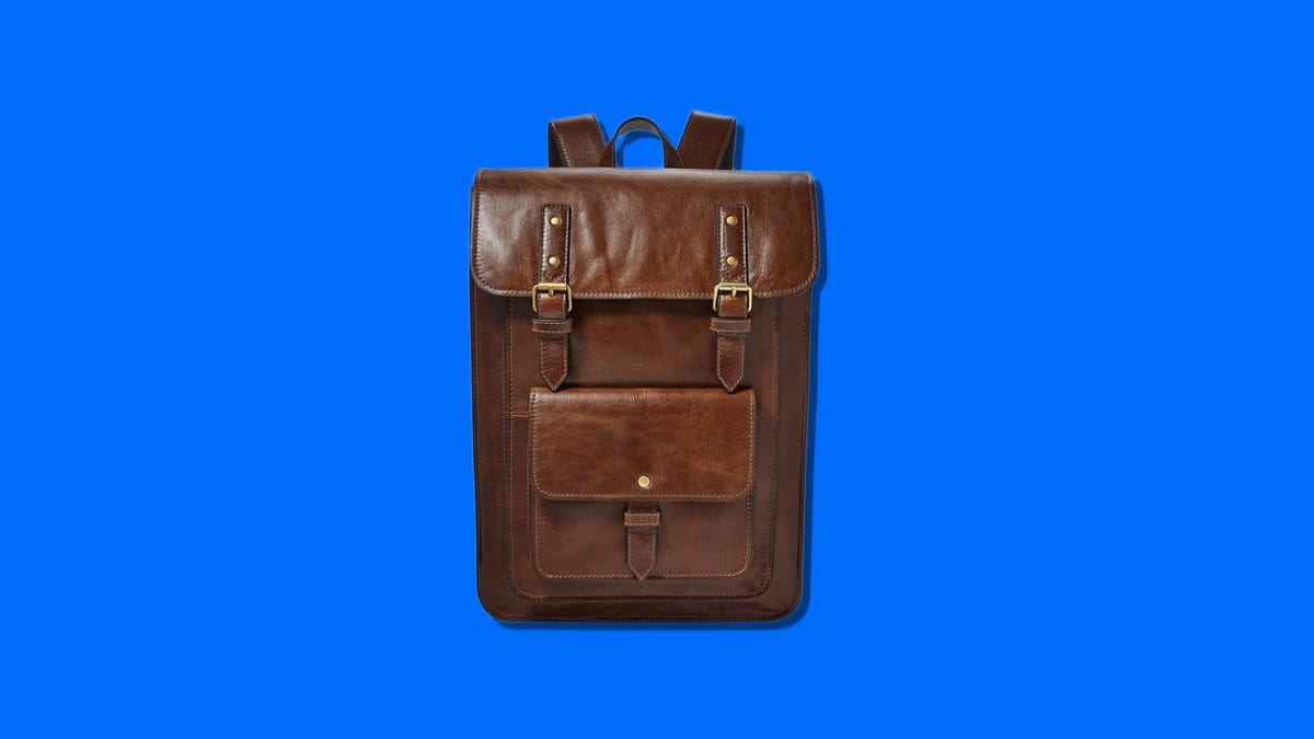 Brown leather backpack with brass buckles on a blue background
