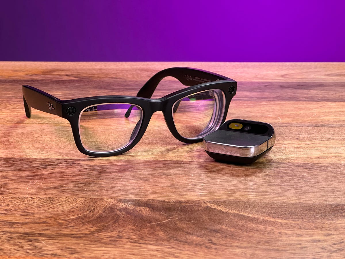 Humane AI Pin and Meta Ray-Ban glasses side by side on a wooden table
