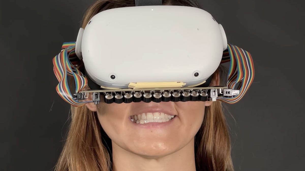 A woman wearing a VR headset with an attachment that sends ultrasound impulses to her mouth
