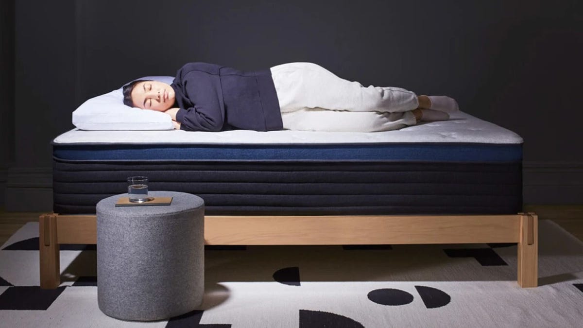 A woman lies on her side on top of a Helix Midnight Luxe mattress.