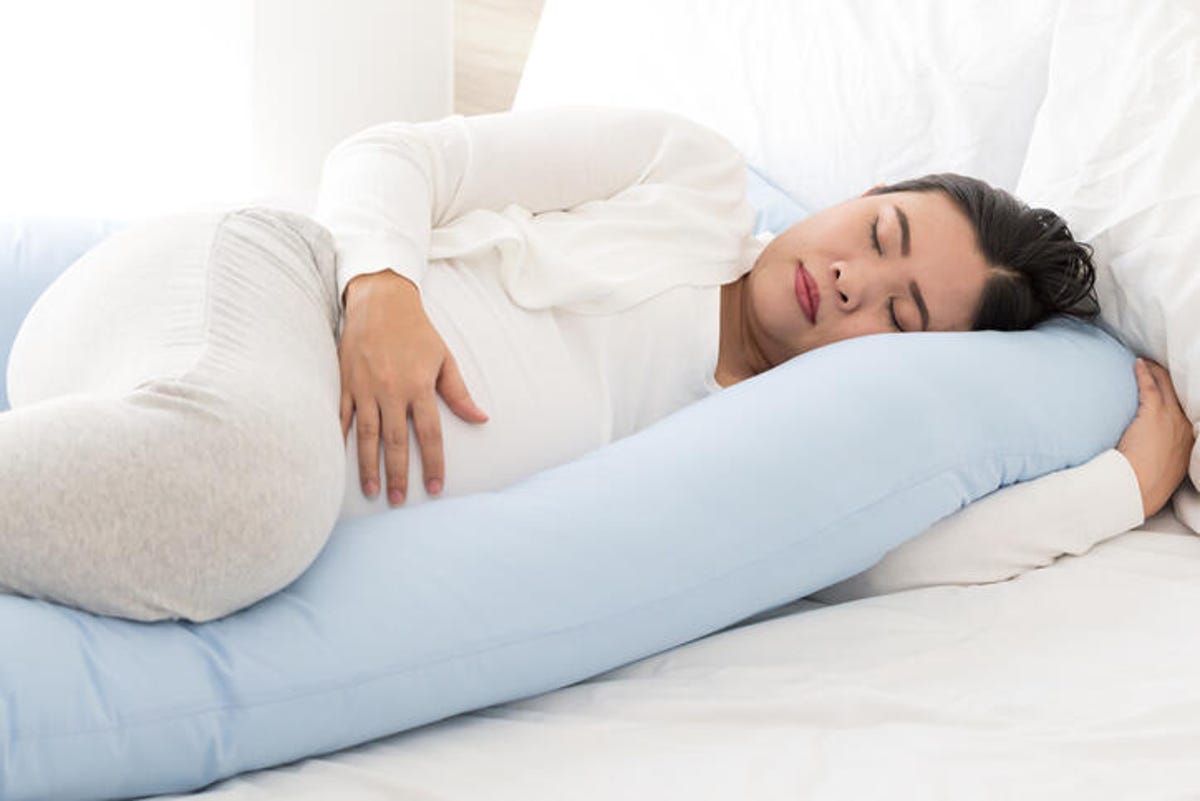 Woman sleeping with a pregnancy pillow between her legs.
