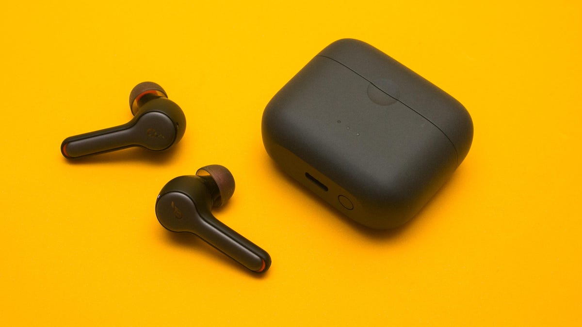 Two Soundcore earbuds and the charging case against a yellow background. 