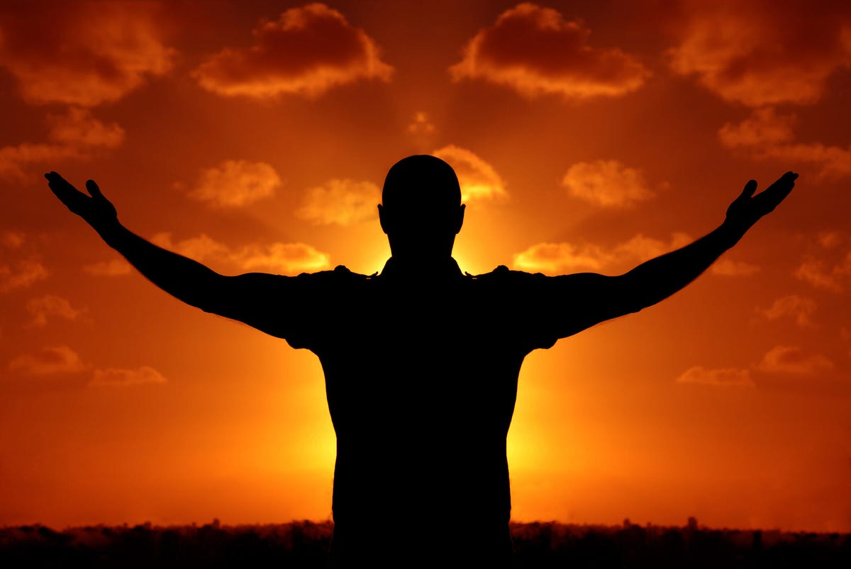 A silhouette of a person from behind, facing a bright orange sunset