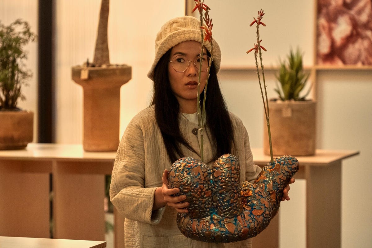 Ali Wong wears a hat and holds a sculpture in a Beef scene