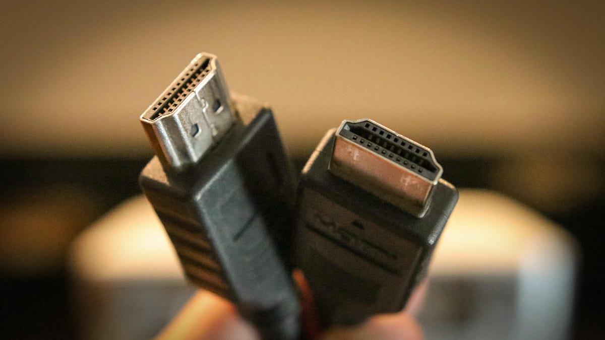 A close-up shot of someone holding two HDMI cables.