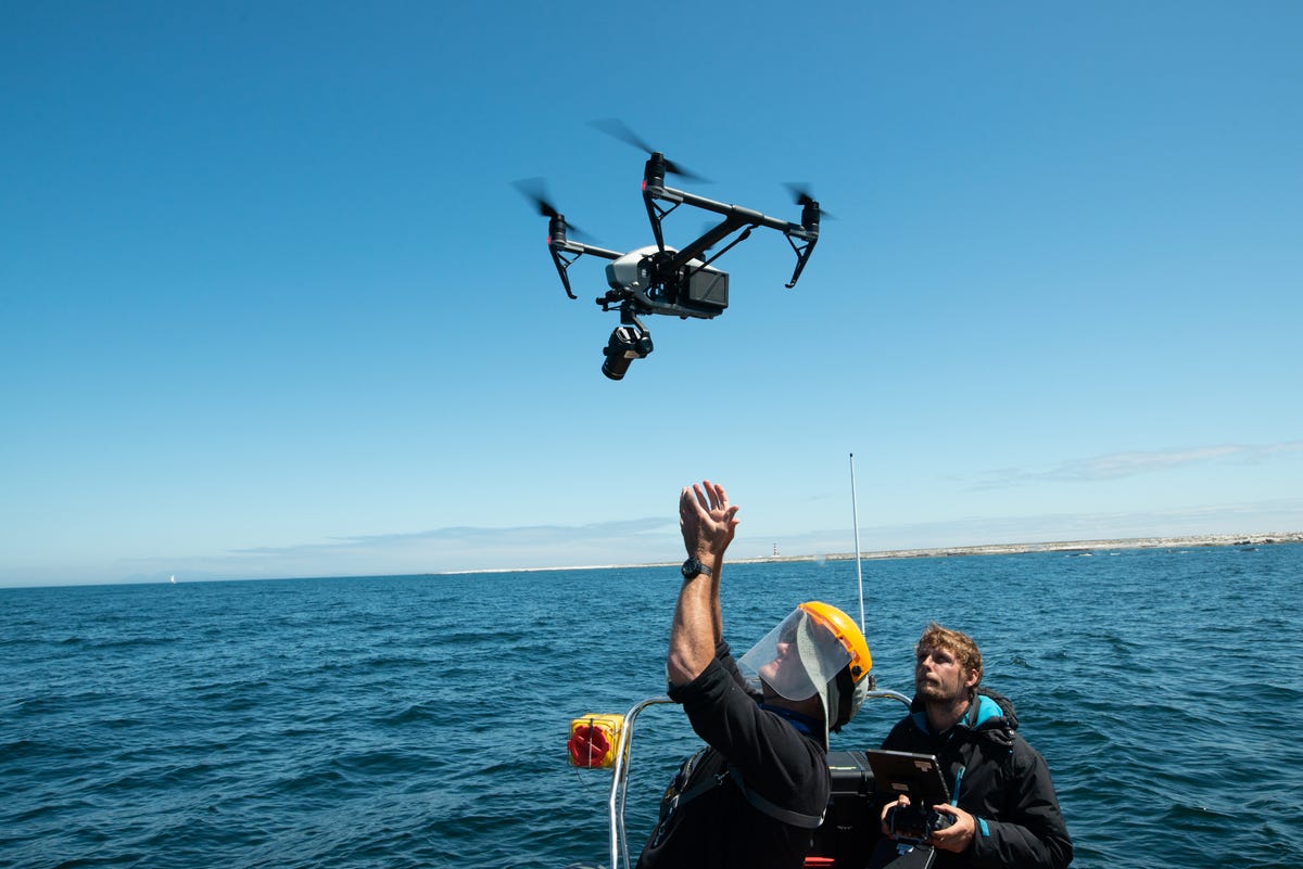 A drone operator catches a drone on a boat in the open ocean.
