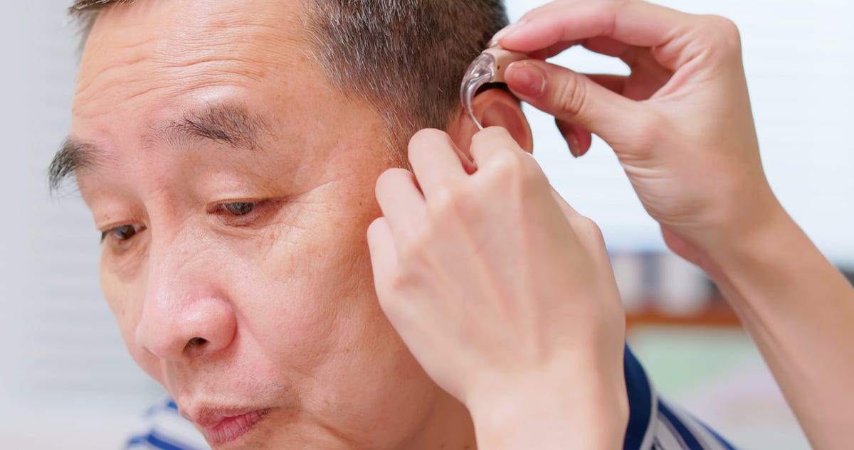 Médico ajuda paciente a usar aparelhos auditivos