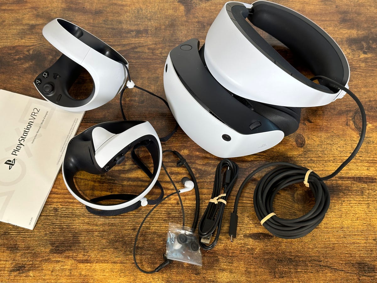 Sony PlayStation VR2 headset and cables, controllers on a wooden table