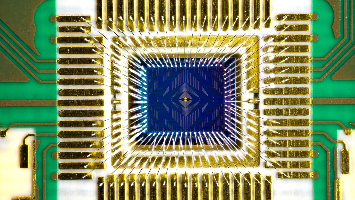 Intel Tunnel Falls quantum computer chip at the center of a circuit board with golden colored electrical communication links