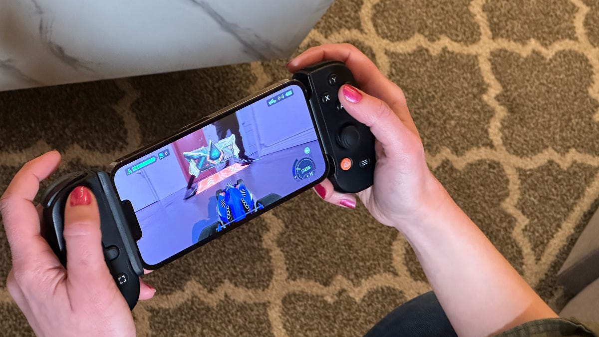 Hands holding an iPhone with a game controller on, playing a racing game