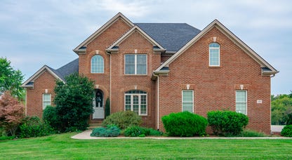a large brick single-family home with a lawn