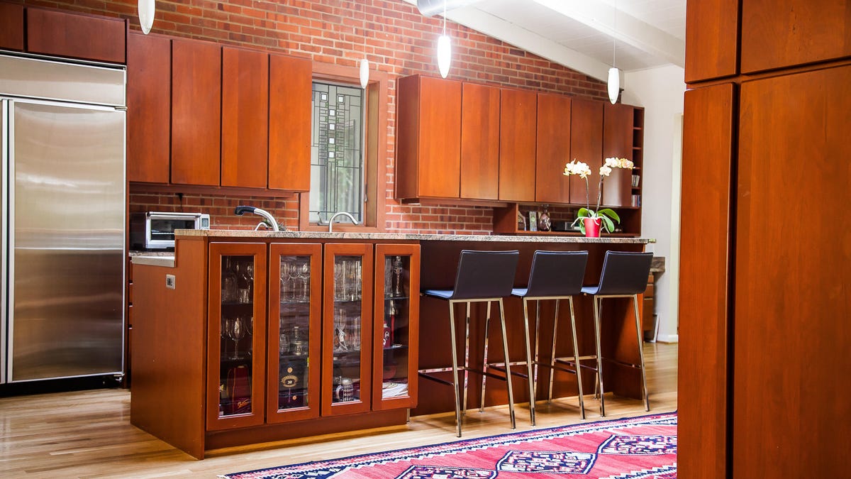 Wide view of kitchen with three stools at the bar and a long runner