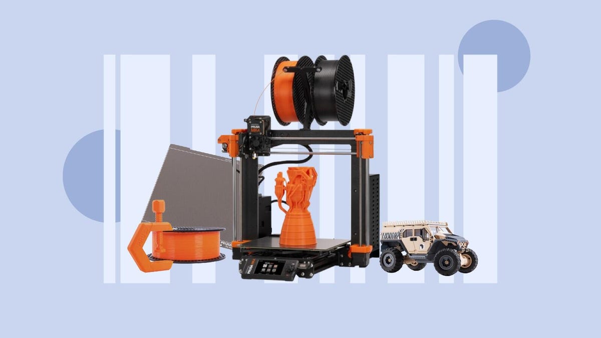 The Prusa Mk4 with a roll of filament, a 3D printed truck and a build plate