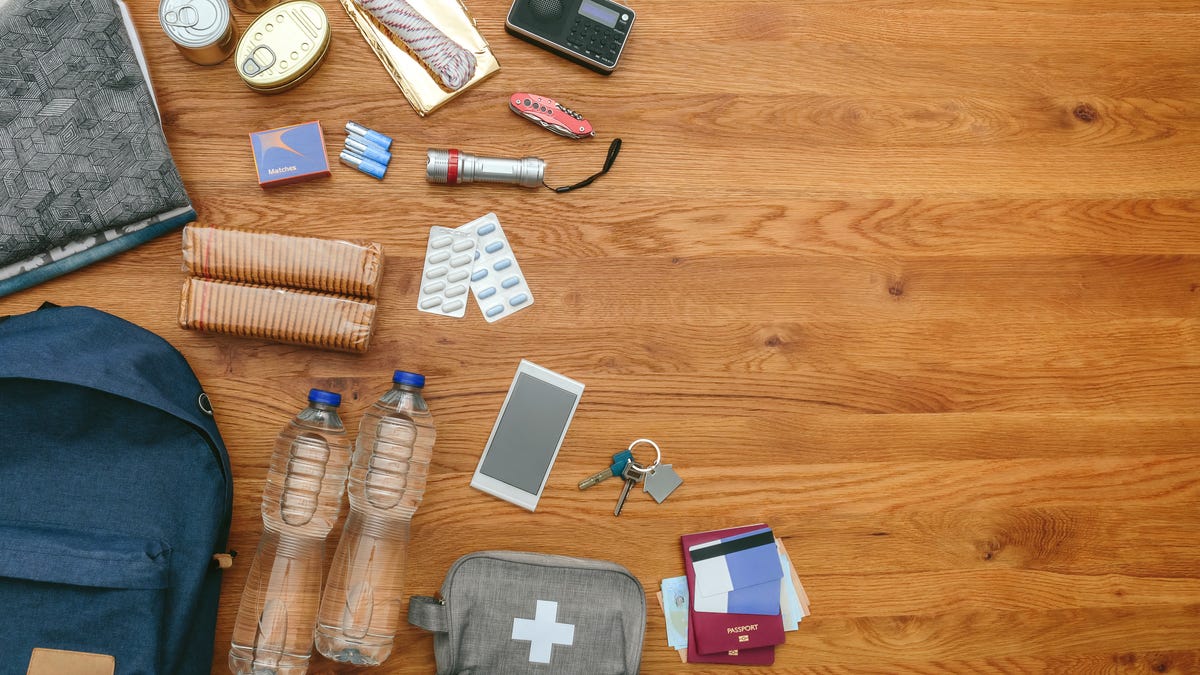 backpack and various emergency supplies laid out on a wooden table