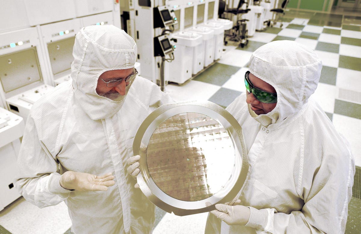 Researchers hold a silicon wafer 300mm in diameter that houses dozens of test chips.