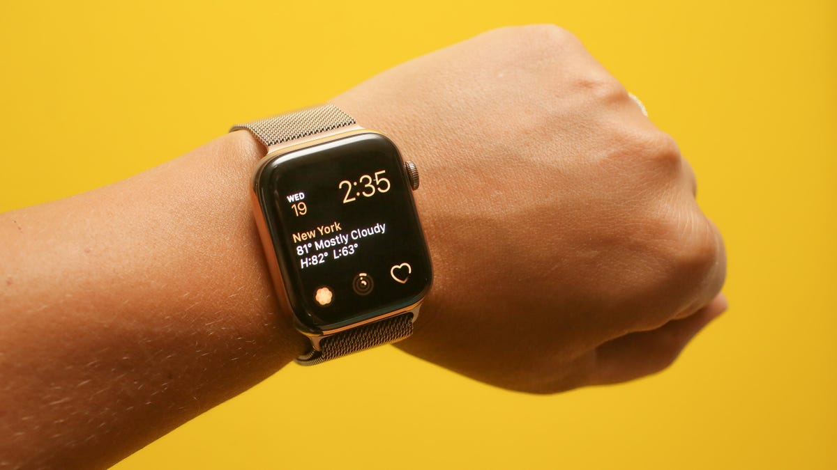 A wrist wearing the Apple Watch Series 4 44mm smartwatch against a yellow background.