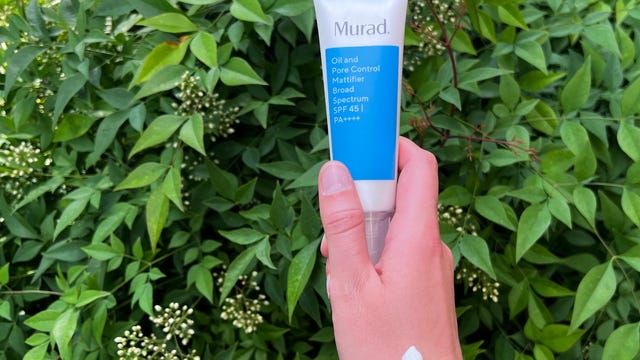 Hand holding Murad Oil and Pore Control sunscreen