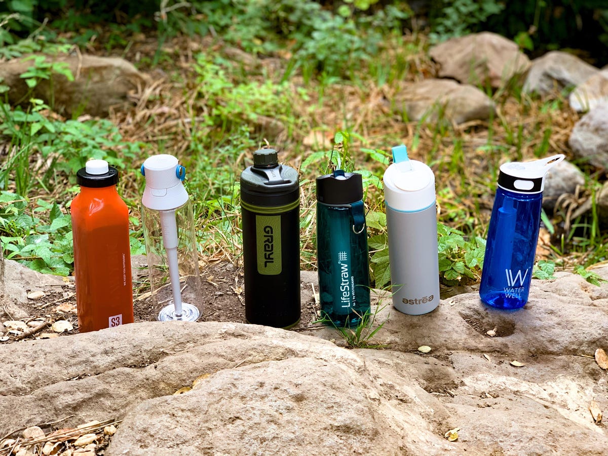 Six filtered water bottles lined up outdoors.
