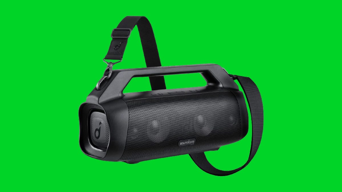 A Motion Boom Plus Bluetooth boom box and carrying strap against a green background.