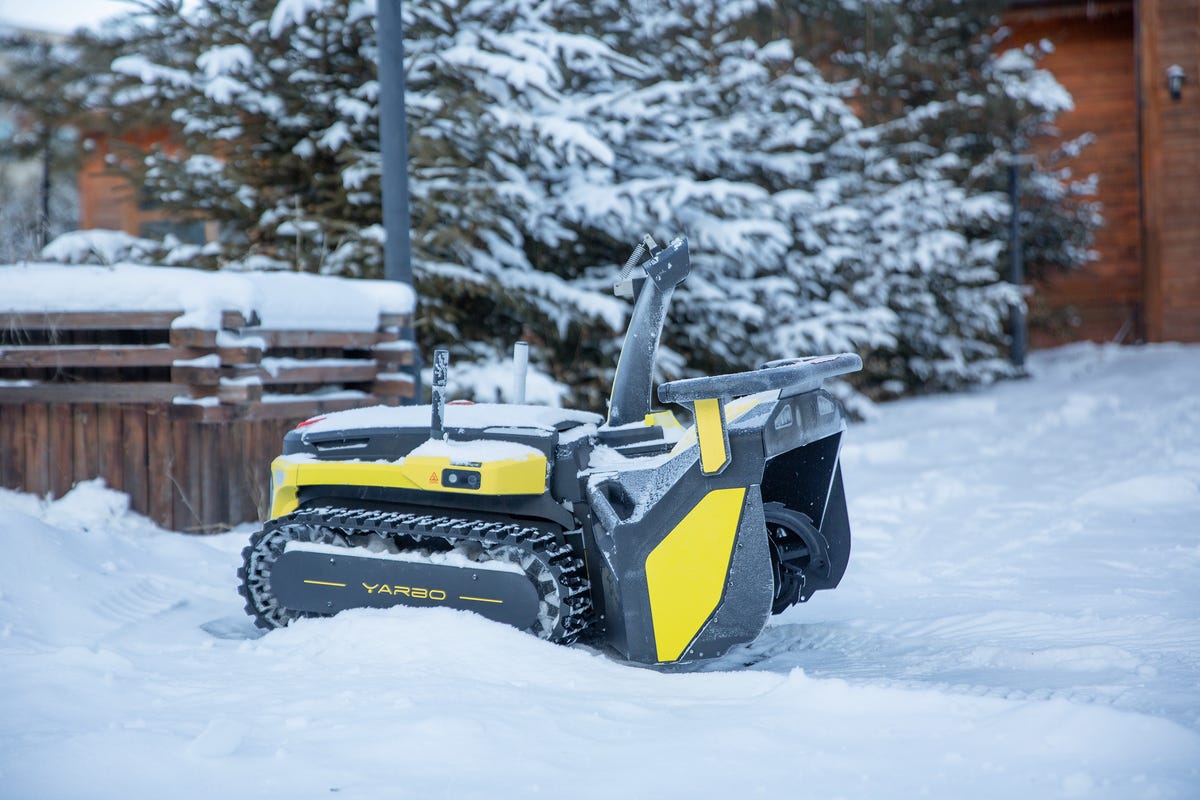 Robot quitanieves que sopla nieve en un patio.