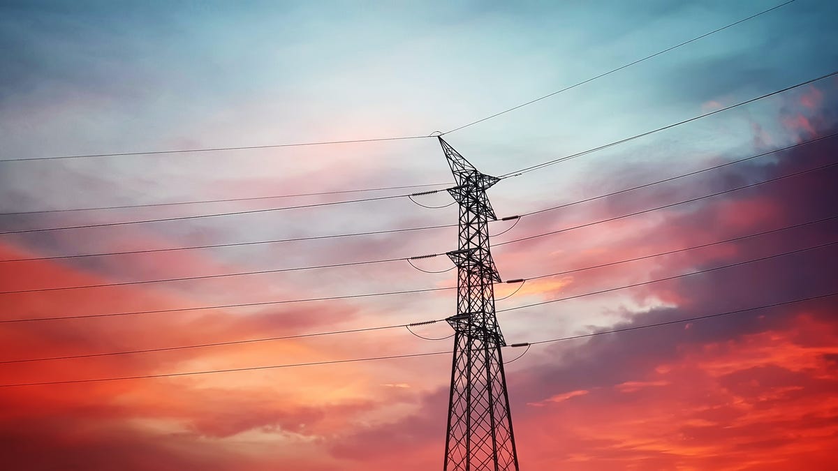 A single electricity tower with a blue and orange sunset in the background