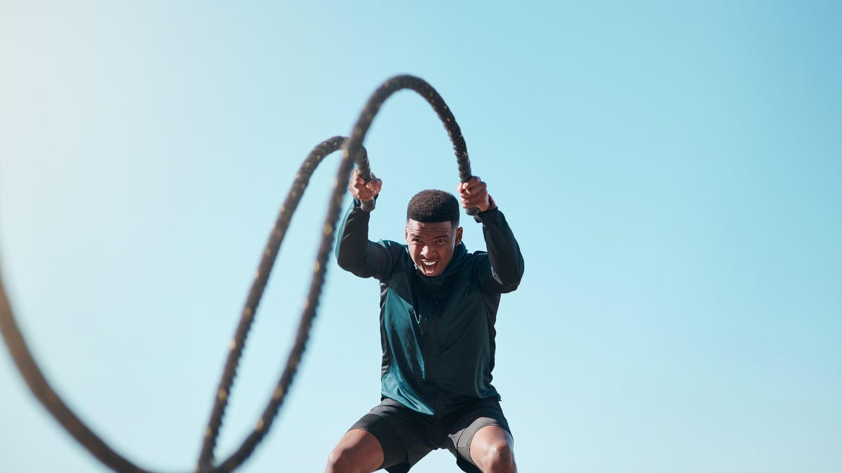a young man doing high intensity exercise with battle ropes outdoors