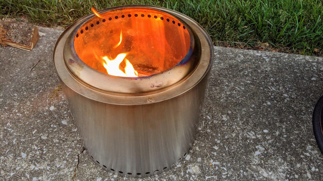A stainless steel Solo Stove Ranger on the groudn outside.