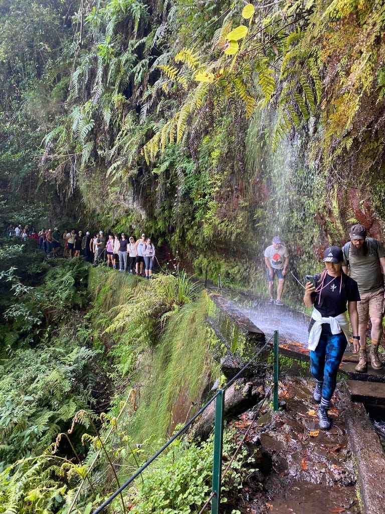 People hiking under a waterfall in Madeira