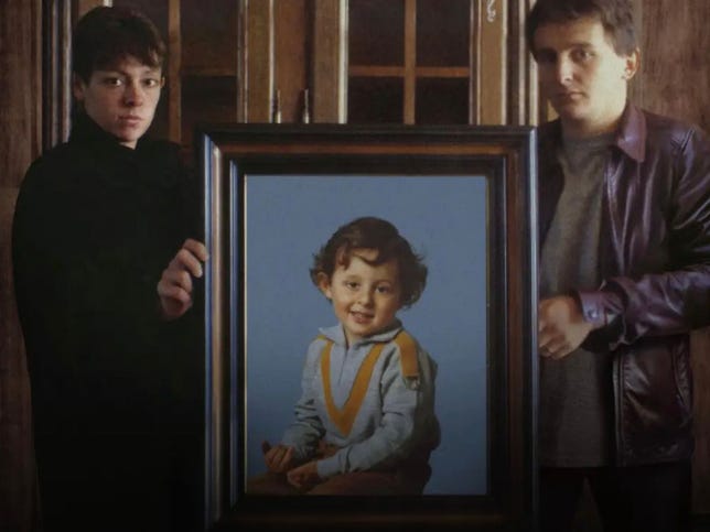 Une photo portrait encadrée de Grégory Villemin, tenue par ses parents