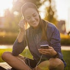 young woman sitting outside picking music for her workout