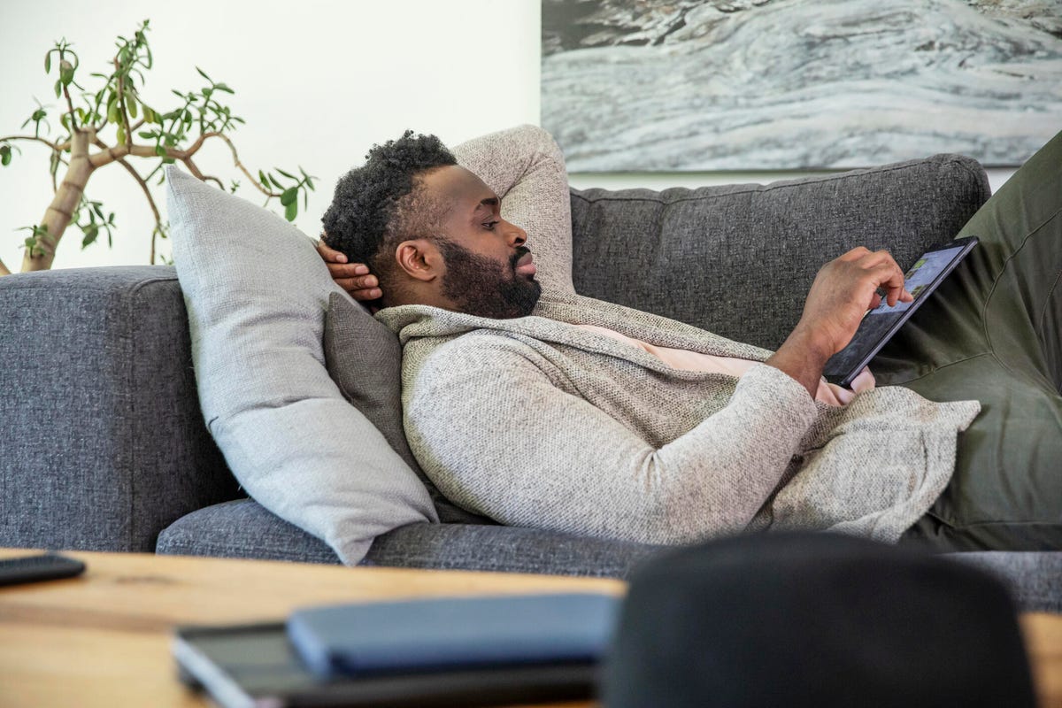 Man reclining on couch using a tablet computer.