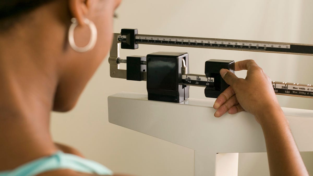 woman checking her weight on a manual scale